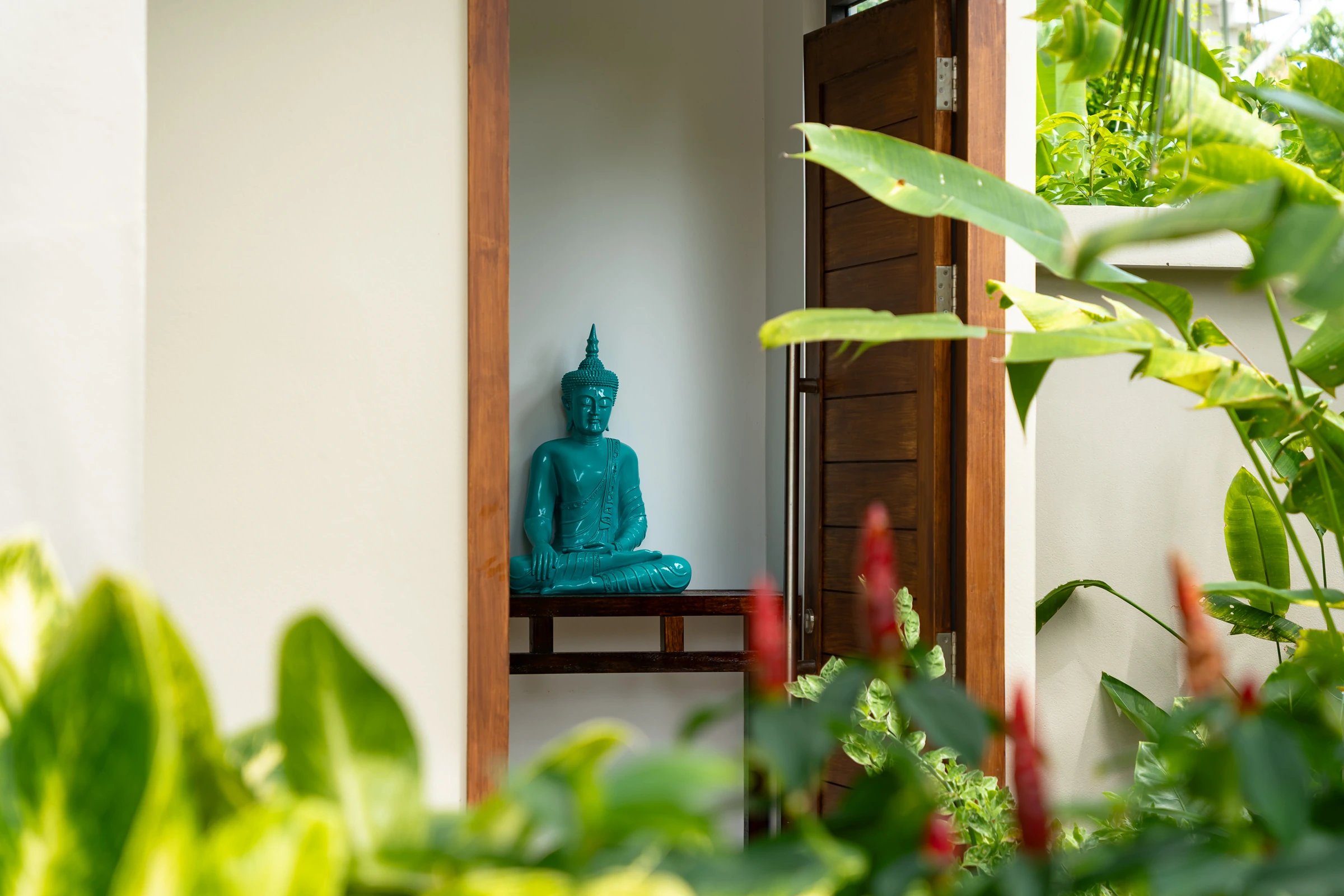 Tropical planting and a turquoise statue beside the villa entrance